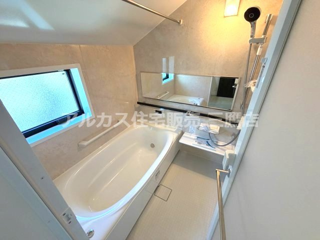 世田谷区北烏山９丁目 京王線 千歳烏山駅 新築戸建の浴室|小窓から自然光が入る明るい浴室。横長ミラーや浴室乾燥用パイプ、手すりなどを備えた快適なバスルームです。