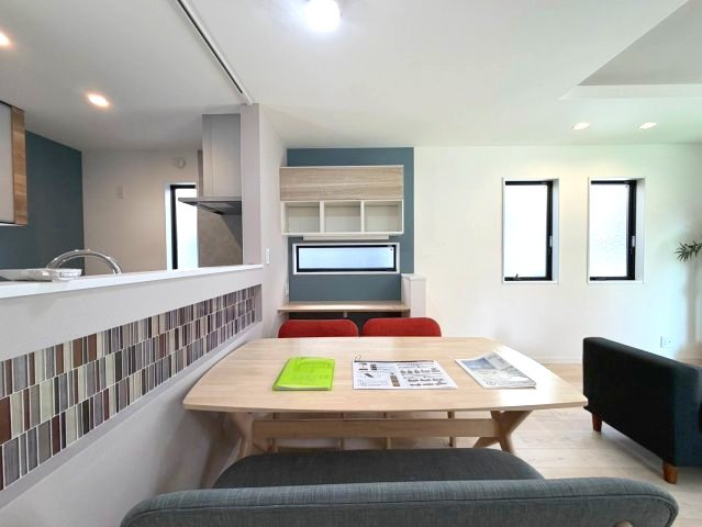 世田谷区北烏山９丁目 京王線 千歳烏山駅 新築戸建の居間・リビング|モザイクタイル調のアクセントクロスが映えるダイニングスペースと奥のワークスペース。※家具・調度品等は販売対象外です。