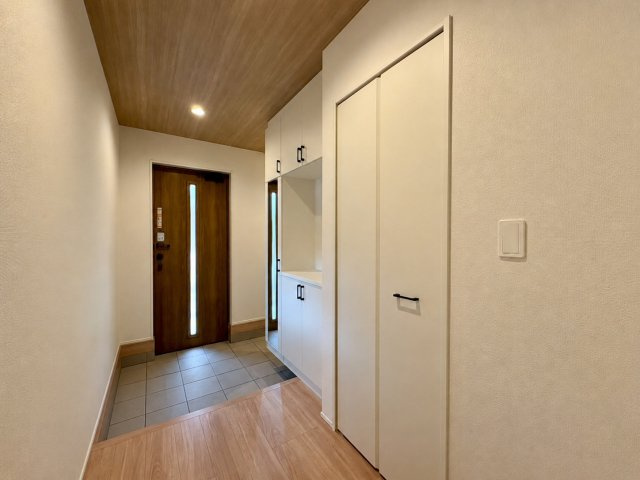 「広々インナーバルコニー」高知市東城山町2号棟　新築一戸建ての玄関|木目調のドアや天井が落ち着いた雰囲気を演出。便利な姿見付きシューズボックス完備。
