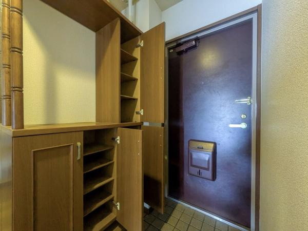 マンション猪野ハイツの玄関|玄関には収納が豊富に備え付けられており整理整頓がしやすい設計です。木目調の収納棚が落ち着いた印象を与えます。玄関ドアには郵便受けも付いており日常の利便性を高めています。