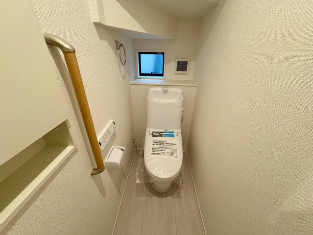 「独立洗面設計」高知市東城山町1号棟　新築一戸建てのトイレ|階段下のスペースを有効活用。手すりや小窓、収納棚も備えた安心で便利な設計です。
