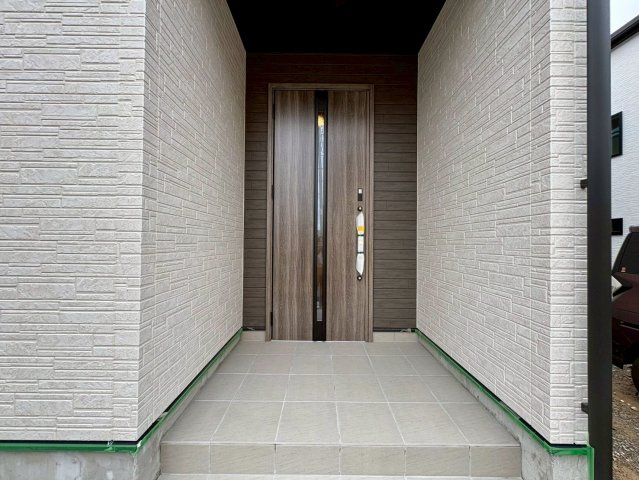 「独立洗面設計」高知市東城山町1号棟　新築一戸建ての玄関|シックな木目調のアクセント壁とドアが調和した、高級感漂う外観デザイン。