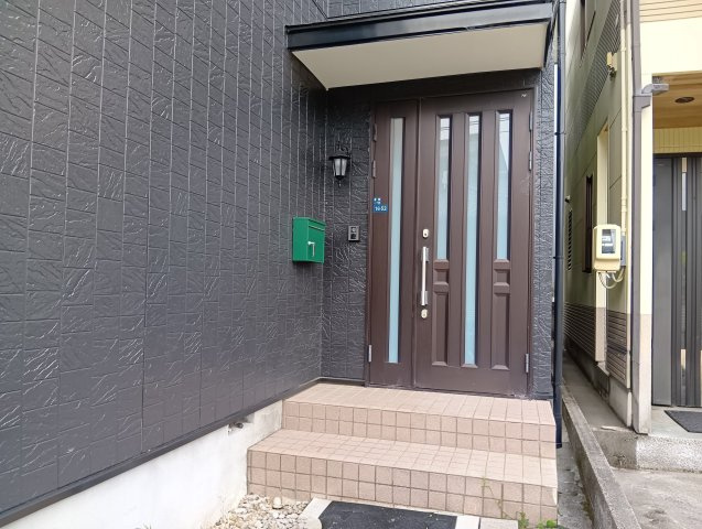売中古戸建　静岡市葵区建穂１丁目の玄関|ダークカラーの外壁に木目調の玄関ドアが映える洗練された外観。採光付きドアから日が差し込み明るい玄関に