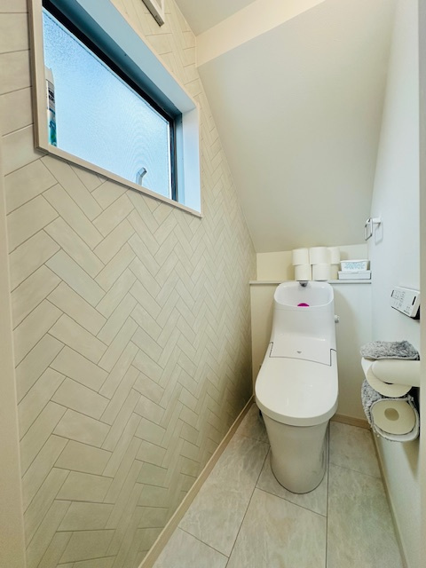 田原本町三笠 中古建てのトイレ|1階レストルーム。
ヘリンボーン長のアクセントクロスと窓からの自然光が調和する、明るく上質なトイレ空間。