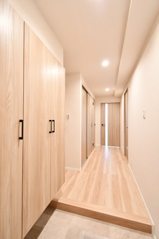 ライオンズマンション春日部南の玄関|玄関から居室へと続く、質感豊かなフローリングが奥行きを演出。ダウンライトの柔らかな光が、リフォーム済みの美しい室内を照らします。扉を開けた瞬間に広がる開放的な住まいを、ぜひ現地でご体感ください。