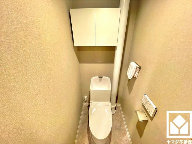ローズハイツ夙川のトイレ|明るく清潔感溢れるトイレです。温水洗浄便座付きで、季節を問わずいつでも温かい便座をお使いいただけます。トイレットペーパーのストックや消耗品置き場などとしてお使いいただける吊戸棚がございます。