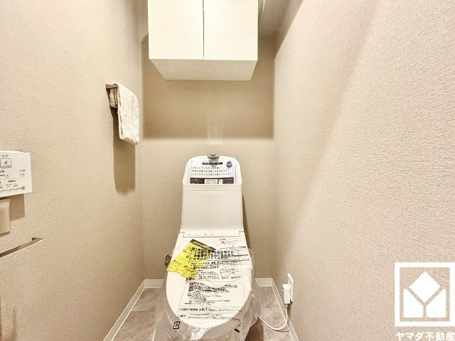 夙川ビューハイツB棟のトイレ|明るく清潔感溢れるトイレです。トイレットペーパーのストックや消耗品置き場などとしてお使いいただける吊戸棚がございます。