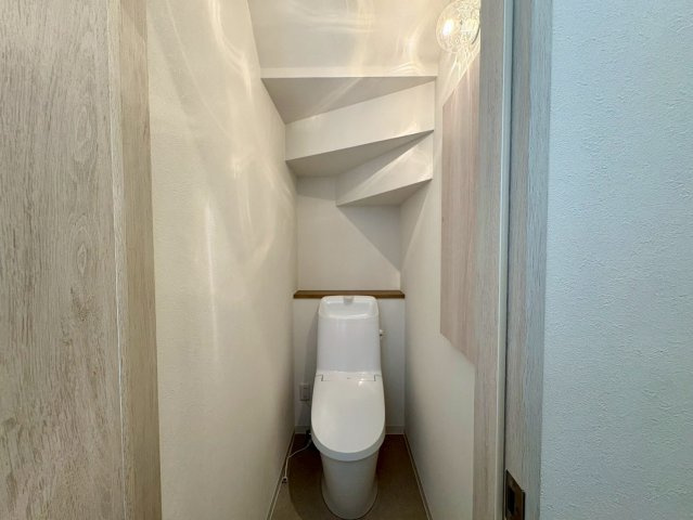 「長期優良住宅」香南市野市町西野　新築戸建　西棟のトイレ|階段下のスペースを有効活用した、手洗い付きのトイレ。照明の光が優しく広がる、落ち着いた空間です。