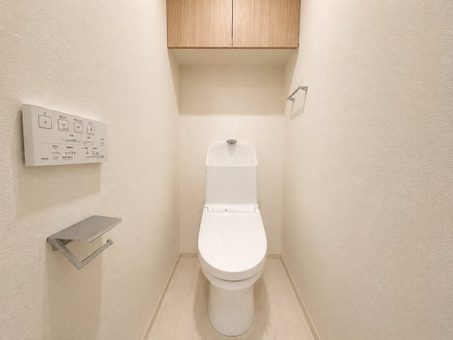 アンビシャス府中武蔵野台のトイレ|吊戸棚も木目調でおしゃれです。フチなしトイレでお掃除も楽々！