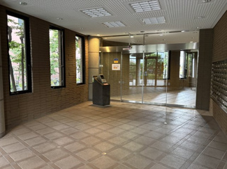 【エントランス】 | サニークレスト武蔵浦和 | 防犯面に配慮された安心のオートロックシステムを搭載。縦長の窓から柔らかな自然光が差し込むロビーは、タイル貼りの床や壁面が気品ある空間を演出します。右側には整然と並ぶメールボックスも配置されています。