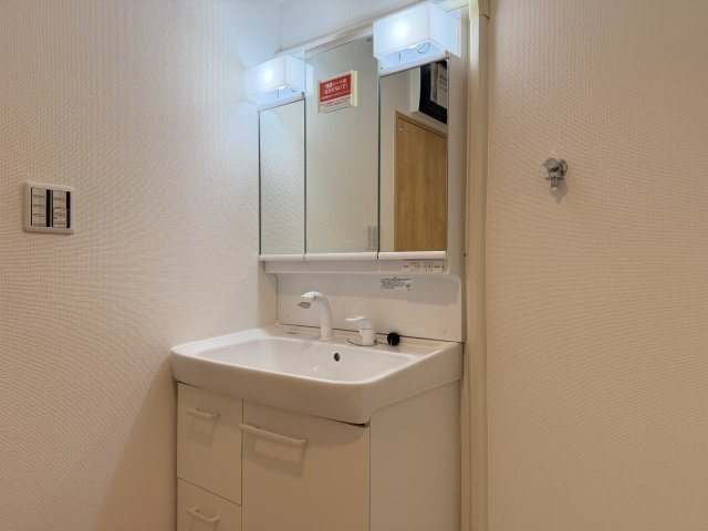 三旺マンション第５植田の独立洗面台|忙しい朝の準備もスムーズにこなせる、収納力抜群の洗面化粧台。三面鏡裏には散らかりがちな小物をたっぷり収納可能。お手入れしやすいボウル形状で、綺麗を楽にキープできる家事ラク仕様です。
