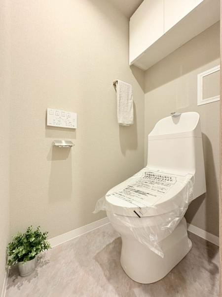 クレストフォルム市が尾南のトイレ|明るく清潔感のあるトイレ空間です。壁付けの操作パネルやペーパーホルダーが設置されています。手洗い付きの便器で使いやすさに配慮されています。収納棚も備え付けられており整理整頓しやすい仕様です。
