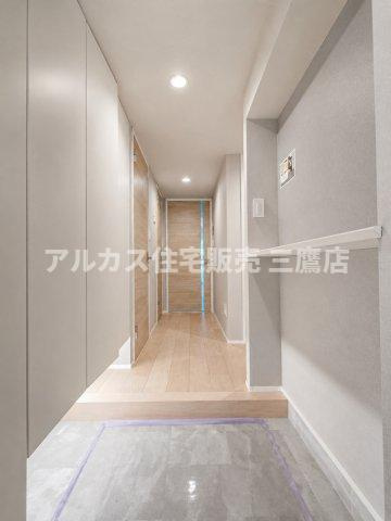デュオ府中駅前の玄関|温かみのある木目調のドアと優しい照明が魅力的で、明るく清潔感のある玄関ホール。