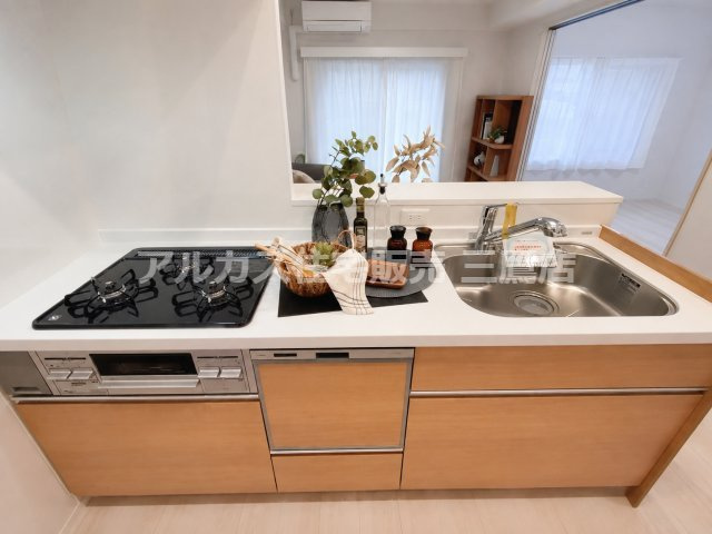 レーヴステージ府中緑町のキッチン| 明るい木目調の扉が印象的なキッチン。作業台と引き出し収納を備え、調理器具を整えやすい設計です。