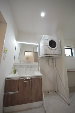 南大河町の独立洗面台|清潔感あふれるシャワー付洗面台と洗面室。鏡の裏には、歯ブラシや化粧品、ドライヤーまでスッキリ収まる大容量の収納スペースがあります。