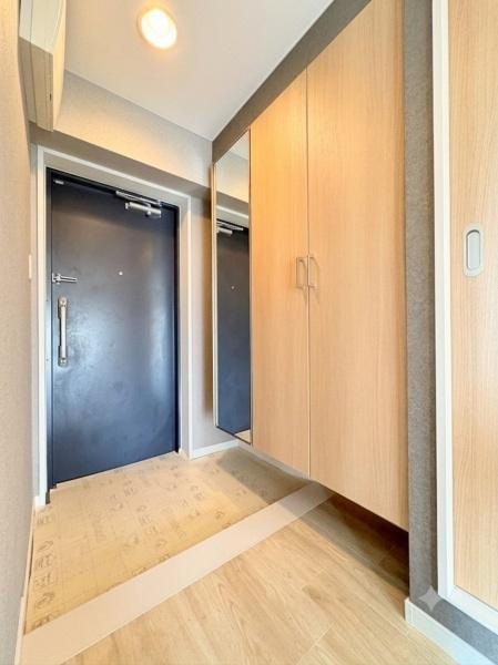 ライオンズマンション大倉山第７の玄関|玄関は明るい雰囲気でミラー付きの収納が備わっています。木目調の扉が温かみを演出します。出入口付近はスペースが確保されていて日々の出入りもスムーズです。フロアや壁も落ち着いた色合いでまとめられています。