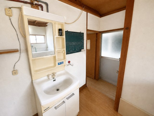 5Kに納戸と土間付｜日南市南郷町潟上・潮風香る港町に佇む戸建の独立洗面台|照明付き鏡を備えた独立洗面化粧台。横に洗濯機用蛇口を配置。