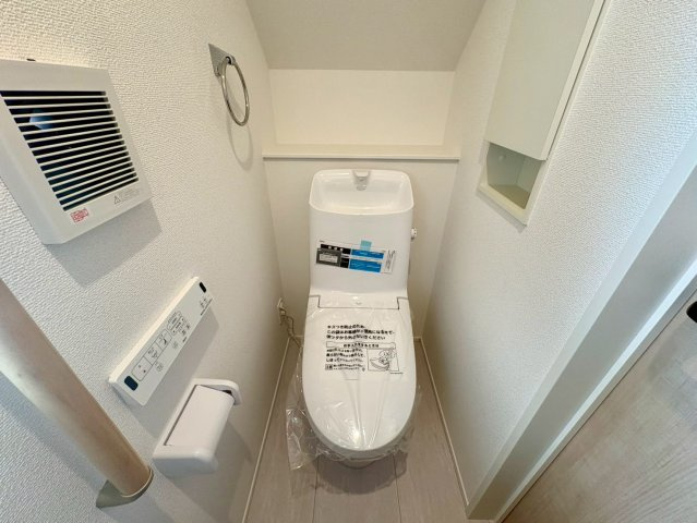 「全居室南向き」高知市介良乙10期3棟2号棟のトイレ|階段下のスペースを有効活用した温水洗浄便座付きトイレ。埋込収納や手すりも備わった快適空間です。