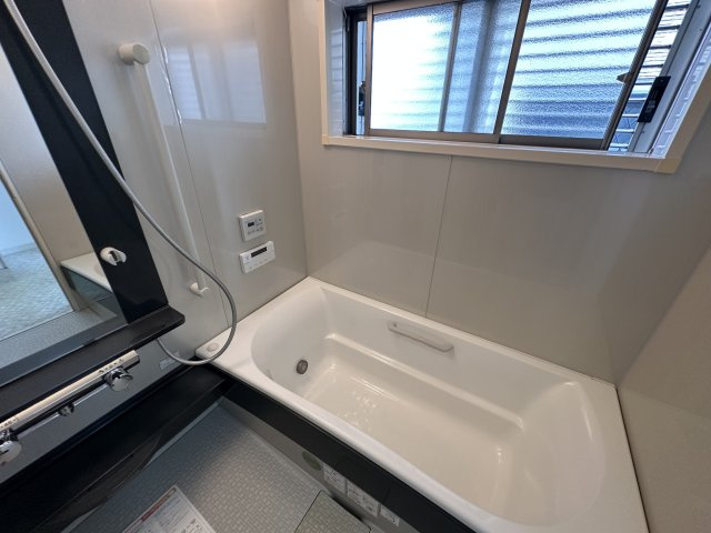 加古川町中津戸建ての浴室|【浴室】
窓付きの浴室です。手すりが設置されており、安全な立ち上がりをサポートします。湯船に浸かりながら給湯器リモコンの操作を行えます。