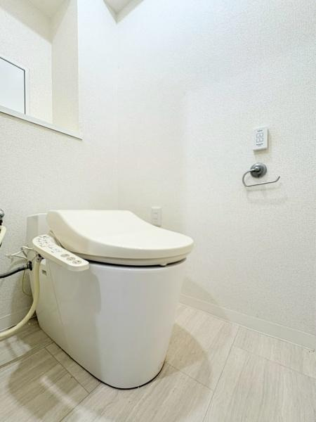 藤和大倉山コープのトイレ|清潔感のある明るいトイレです。壁と床の色合いが落ち着いた雰囲気を演出しています。温水洗浄便座が設置されています。スペースにゆとりがあり使い勝手が良いです。収納スペースも備わっています。