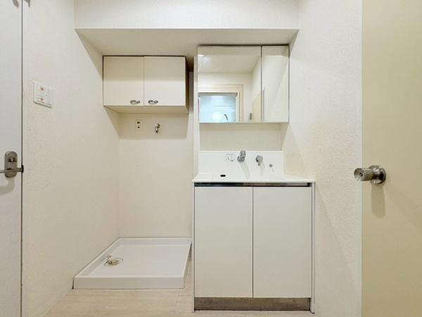 藤和大倉山コープの独立洗面台|鏡付きの洗面台と収納が設けられています。白を基調としたシンプルなデザインです。洗濯機置場もあり使い勝手が良い印象です。空間がすっきりとまとまっています。