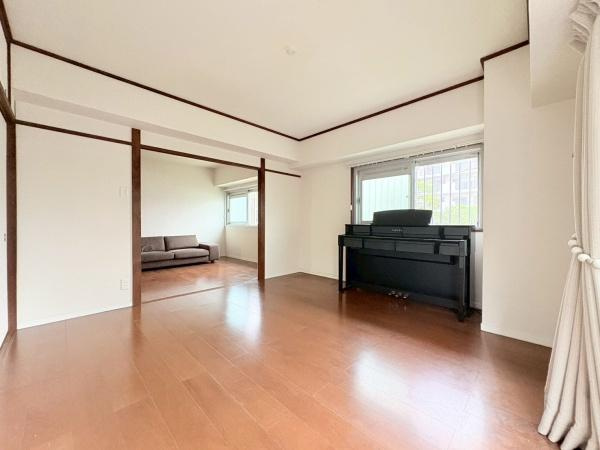 藤和大倉山コープの寝室|広々とした寝室には大きな窓があり開放感を感じられます。床はシンプルな木目調で合わせやすい雰囲気です。奥にはシンプルなソファスペースがあり使い勝手の良いレイアウトです。
