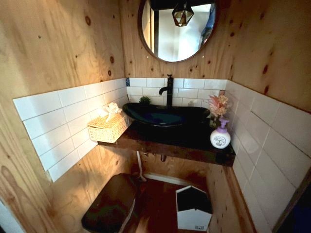 国道アクセス良好。天窓付LDK・テラス完備の多用途な平屋～鹿児島市小山田町～の独立洗面台|丸型ミラーを採用。木の質感とタイルを組み合わせた洗面台