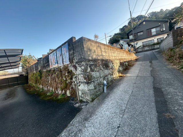 国道アクセス良好。天窓付LDK・テラス完備の多用途な平屋～鹿児島市小山田町～の前面道路含む現地写真|西側の接面道路。高低差を活かした石積みによる外構