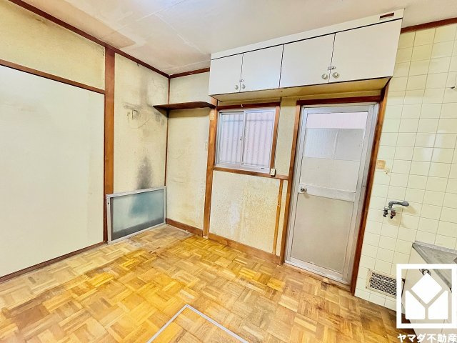 西宮市甲子園町の居間・リビング|キッチン横には勝手口があり、換気やゴミ出しなどに便利です。上部には吊戸棚も設置されており、スッキリとした空間が保てます。