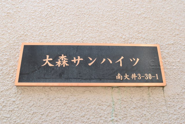【現況写真】 | 大森サンハイツ | エントランスに掲げられた、マンション名を示す館銘板。さほど激しく主張はしませんが、しっかりと掲示されています。～即日のご見学可能～　お問合せはお気軽にどうぞ。