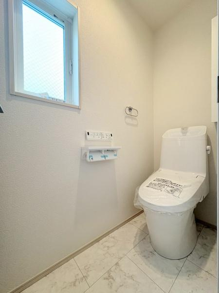 横浜市港北区鳥山町の新築一戸建のトイレ|明るい窓から光が差し込むトイレです。シンプルな内装で清潔感があります。壁付けのペーパーホルダーやリモコンが使いやすい位置に設置されています。床はお手入れしやすい素材となっています。