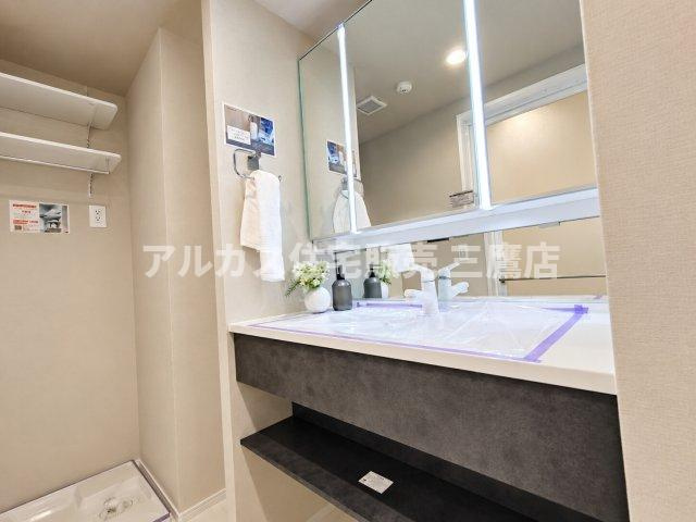 D’クラディアひばりが丘RESIDENCEの独立洗面台|モダンなスタイリングの洗面化粧台と洗濯機置き場のある脱衣スペース。可動棚も備わり、タオルや洗剤などの収納にも便利です。   