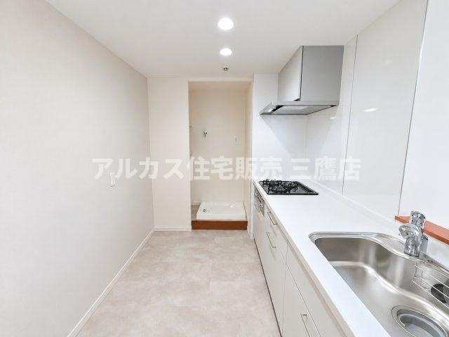 コトー田無のキッチン|白を基調とした清潔感あふれるキッチン空間で、奥には洗濯機置場が配置されたスムーズな家事動線が魅力です。