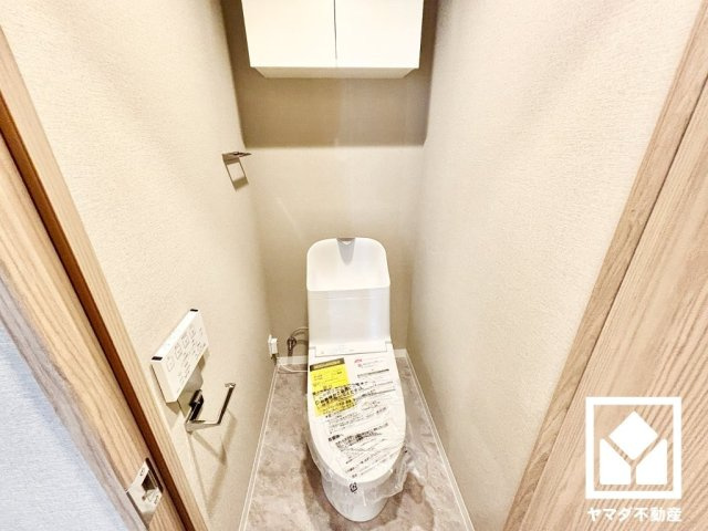 西宮セントポリア1号棟のトイレ|明るく清潔感溢れるトイレです。温水洗浄便座付きで、季節を問わずいつでも温かい便座をお使いいただけます。トイレットペーパーのストックや消耗品置き場などとしてお使いいただける吊戸棚も備えています。