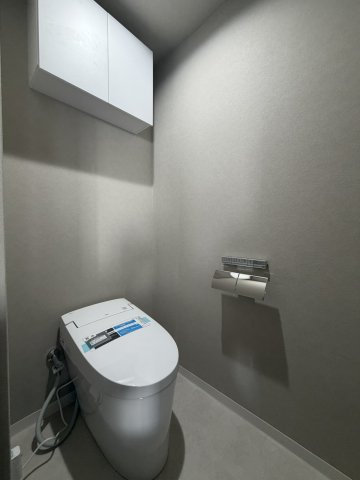 ヴェルト日本橋Ⅱのトイレ|落ち着いたアクセントクロスが上質な空間を演出するトイレ。温水洗浄便座付きで快適な使い心地を実現し、吊戸棚も備えているため、生活用品をすっきり収納できます。