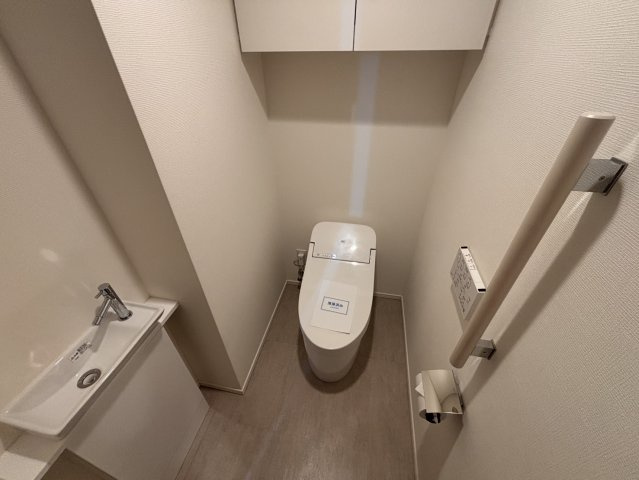 快適な温水洗浄便座付きのトイレです。手洗いカウンターを完備し、上部には便利な吊戸棚を備えた機能的な設計。清潔感のある落ち着いた空間、手すりも設置されており、どなた様にも使いやすい配慮がなされています。