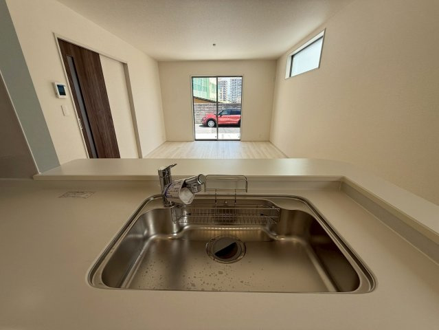 リーブルガーデン与那原町与那原・４号棟のキッチン|浄水器付きキッチンの流し台／キッチンからリビングの眺め