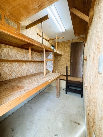 吉川市　二ツ沼　中古戸建の収納|【1階・物置】棚や作業台が設けられた、ゆとりある1階物置。アウトドア用品や工具、季節物などをまとめて収納しやすく、作業スペースとしても活用できます。