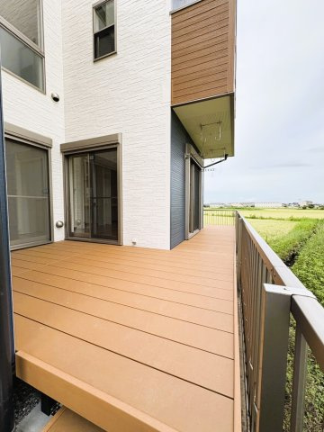 吉川市　二ツ沼　中古戸建のその他|【1階・ウッドデッキ】建物沿いにゆったりと設けられた1階ウッドデッキ。室内から出入りしやすく、洗濯物を干すスペースとしてはもちろん、椅子やテーブルを置いて外時間を楽しむ場所としても活用できます。