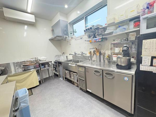 角子原　店舗兼住宅のキッチン|キッチンはステンレス製の作業台や収納が充実しており調理器具も整理され使いやすい印象です。広い作業スペースで調理がしやすく設備も揃っています。窓があり採光を確保しやすい環境です。