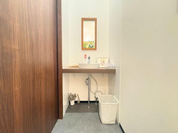 角子原　店舗兼住宅の独立洗面台|洗面台がすっきりとしたデザインでまとまっています。鏡が設置されていて圧迫感がありません。床材の色味が落ち着いた印象を与えます。