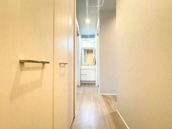 角子原　店舗兼住宅の内装|明るい色合いのフローリングと壁面がすっきりとした印象を与えます。収納スペースもしっかり確保されています。廊下を抜けた先に洗面台が配置されており動線も便利です。シンプルなデザインで統一されています。