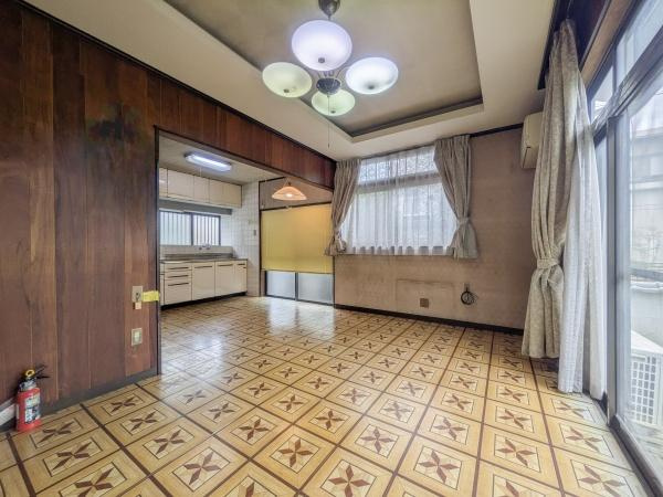 皆春　戸建ての居間・リビング|落ち着いた木目調の壁が印象的です。
キッチンへの動線もスムーズです。