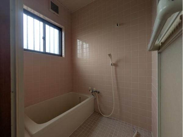 皆春　戸建ての浴室|淡い色合いのタイルが特徴的なバスルームです。窓から自然光が入り空間に明るさを感じます。浴槽とシャワーが完備されており日々の利用に便利です。換気口も設置されているため快適な状態を保ちやすい仕様です。