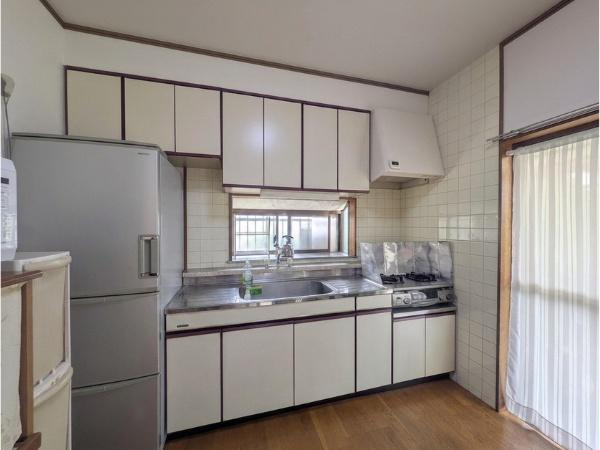 皆春　戸建てのキッチン|窓のあるキッチンで明るい空間が広がっています。収納が充実しており作業スペースも確保されています。冷蔵庫や家電の設置もしやすいレイアウトです。シンプルなデザインでお手入れもしやすい仕様となっています。