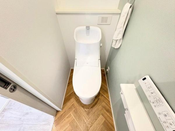 丹生　戸建てのトイレ|白を基調とした清潔感のあるトイレです。木目調の床が空間に温もりを与えます。手洗い一体型のデザインが特徴です。収納スペースも実用的です。