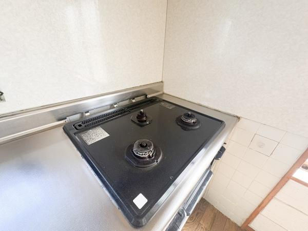 富士見が丘西4丁目中古のキッチン|三口タイプのガスコンロが設置されているため効率よく調理が進められます。お手入れしやすいフラットな天板仕様です。壁面にはタイルが使用されており清掃も簡単です。調理スペースがしっかり確保されています。