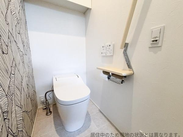 丹生中古のトイレ|壁のアクセントクロスがおしゃれなトイレ。手すりや棚も備わっており利便性が感じられます。