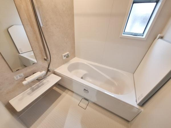 森1号新築建売住宅の浴室|清潔感のある明るいバスルームです。大きなミラーと便利な棚が配置されています。窓付きで換気も考えられています。浴槽はゆったりとしたサイズで快適な仕様です。使いやすさにも配慮されたデザインです。