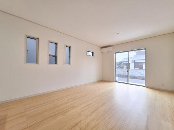 森1号新築建売住宅の居間・リビング|大きな窓から明るい光が差し込むリビングです。ナチュラルなフローリングが空間を広く感じさせます。シンプルな壁面が多彩なレイアウトに対応可能です。快適なエアコンも設置されています。